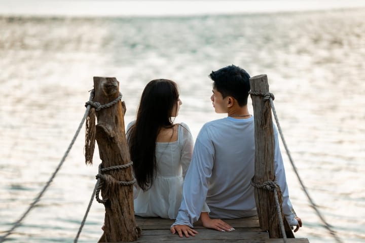 asian couple sitting on a dock