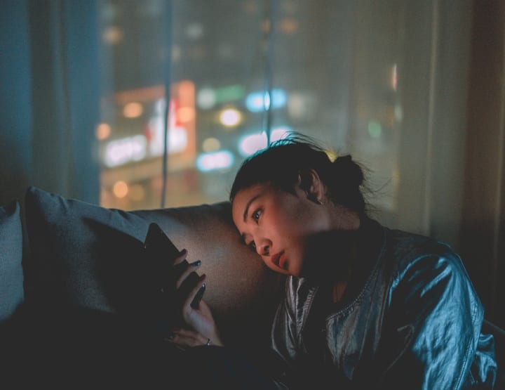girl texting on sofa in the dark