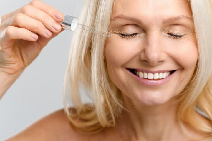 older woman applying serum to fine lines