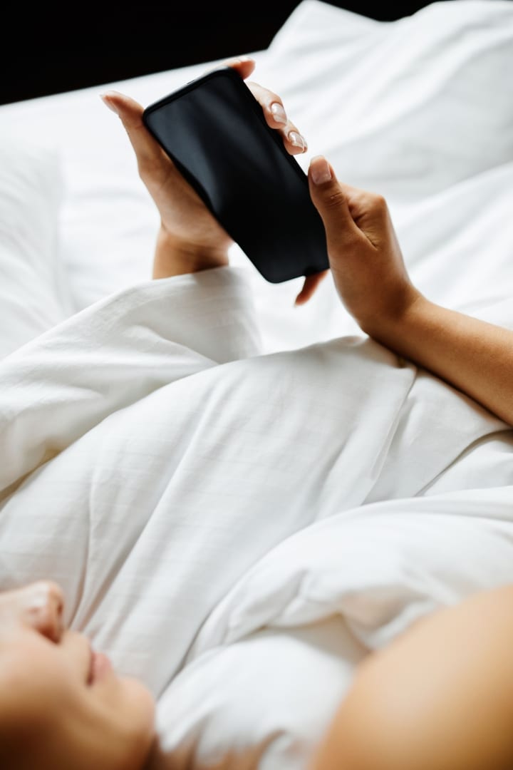 woman watching something on her phone while in bed